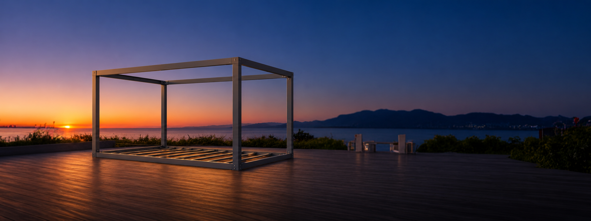 Ubloc steel frame kit on a timber deck beside a lake at sunset; frame-only kit with exposed floor joists.